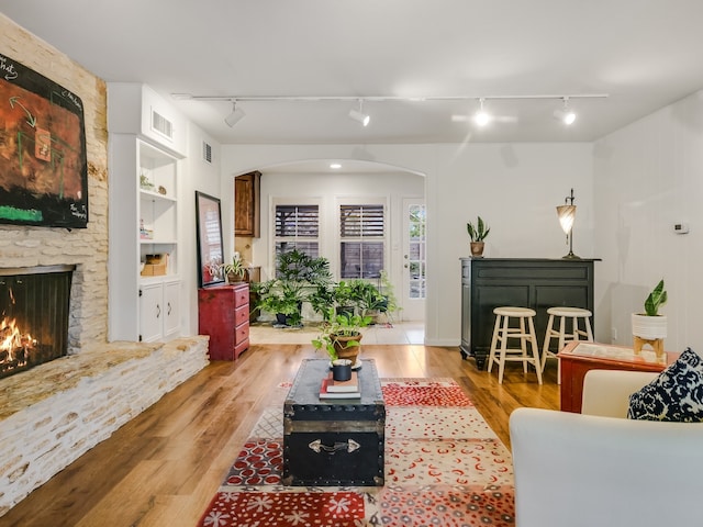 living room with a fireplace, built in features, and light wood-type flooring