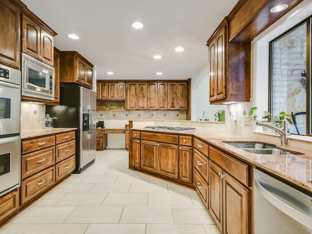 kitchen featuring light stone counters, sink, appliances with stainless steel finishes, and tasteful backsplash