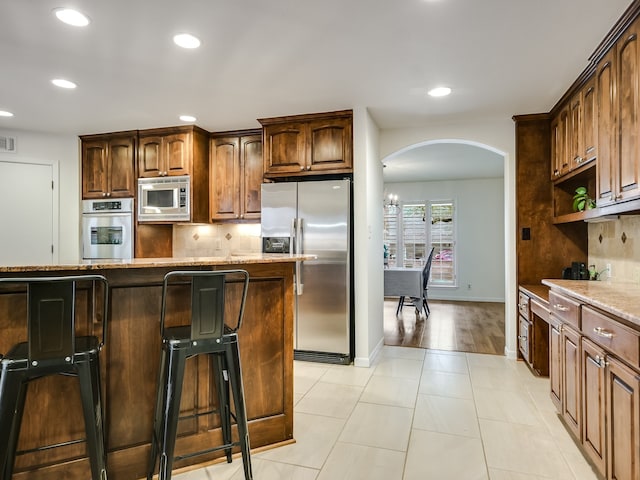 kitchen with appliances with stainless steel finishes, tasteful backsplash, a breakfast bar, and a center island