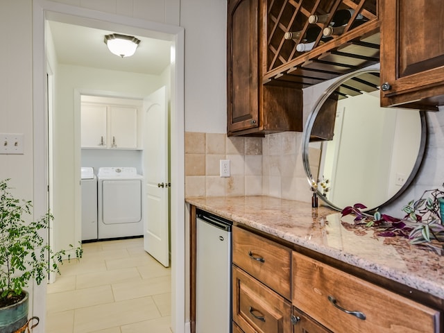 kitchen with washing machine and dryer, light tile patterned floors, fridge, and light stone countertops