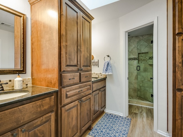 bathroom featuring a shower with shower door, hardwood / wood-style flooring, and vanity