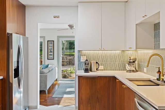 kitchen featuring stainless steel appliances, white cabinets, sink, and backsplash