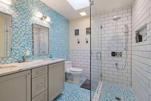 bathroom featuring tile patterned flooring, toilet, a skylight, a shower with door, and vanity