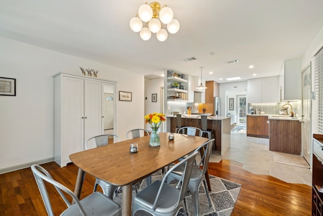 dining space featuring sink, light wood-type flooring, and a notable chandelier