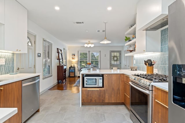 kitchen with white cabinets, appliances with stainless steel finishes, decorative backsplash, and hanging light fixtures