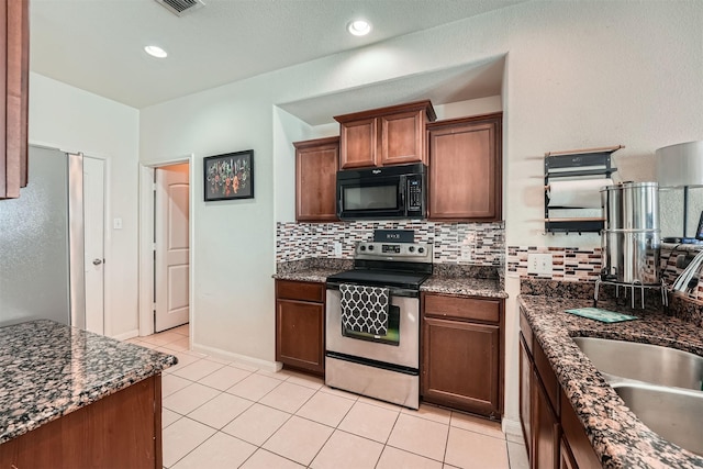 kitchen with dark stone counters, stainless steel appliances, light tile patterned flooring, and decorative backsplash