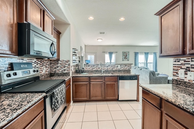 kitchen with sink, stainless steel appliances, light tile patterned flooring, and tasteful backsplash