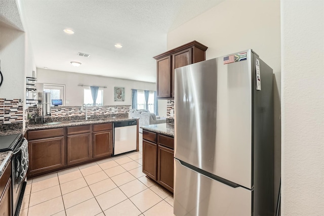 kitchen featuring stainless steel appliances, sink, light tile patterned floors, backsplash, and dark brown cabinetry