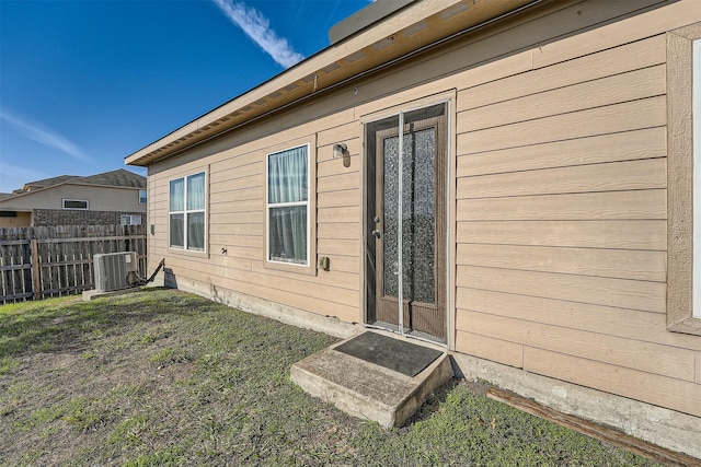 doorway to property featuring central AC and a lawn