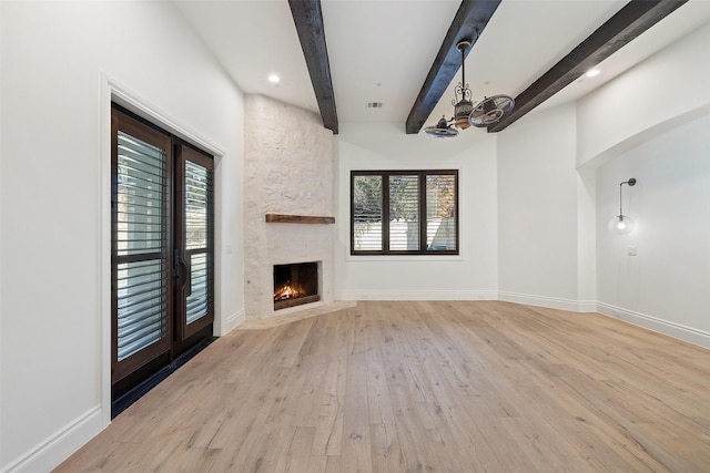 unfurnished living room with a fireplace, beam ceiling, light hardwood / wood-style flooring, and a chandelier