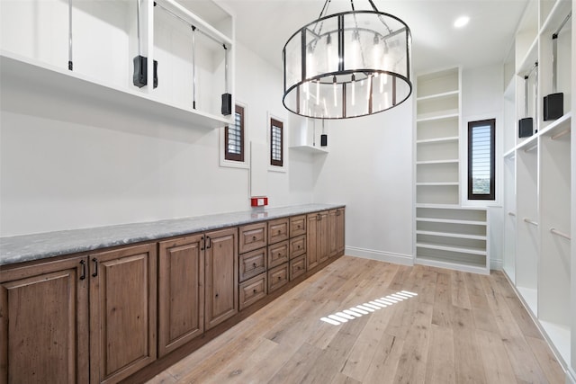 interior space with pendant lighting, a notable chandelier, and light hardwood / wood-style flooring