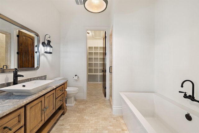 bathroom featuring toilet, a tub to relax in, and vanity