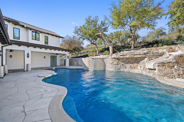 view of pool featuring a water slide and a patio