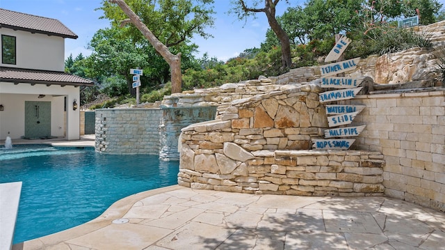 view of swimming pool featuring pool water feature and a patio area