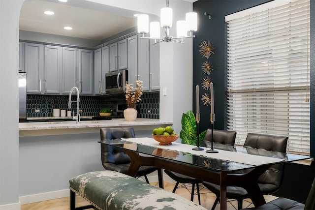 kitchen featuring decorative light fixtures, stainless steel appliances, backsplash, gray cabinetry, and sink