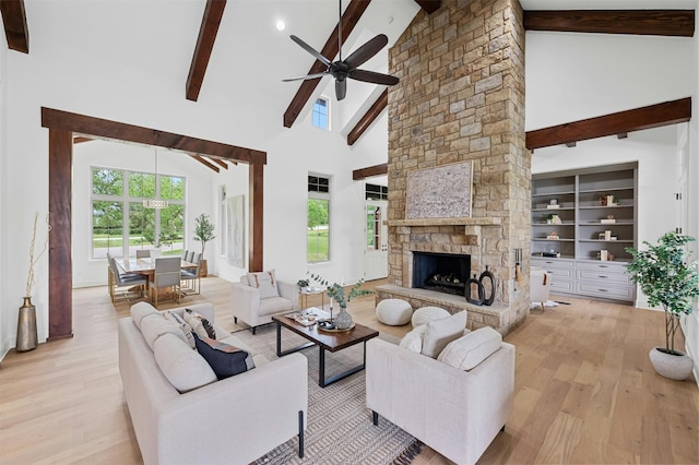 living room with high vaulted ceiling, a fireplace, light wood-type flooring, and beam ceiling