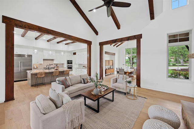 living room featuring sink, a high ceiling, ceiling fan, and light wood-type flooring