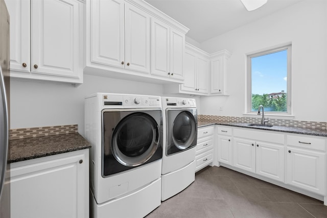 laundry area featuring washing machine and dryer, light tile patterned flooring, cabinets, and sink