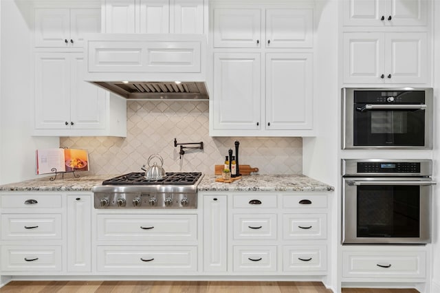 kitchen with appliances with stainless steel finishes, light stone counters, and backsplash