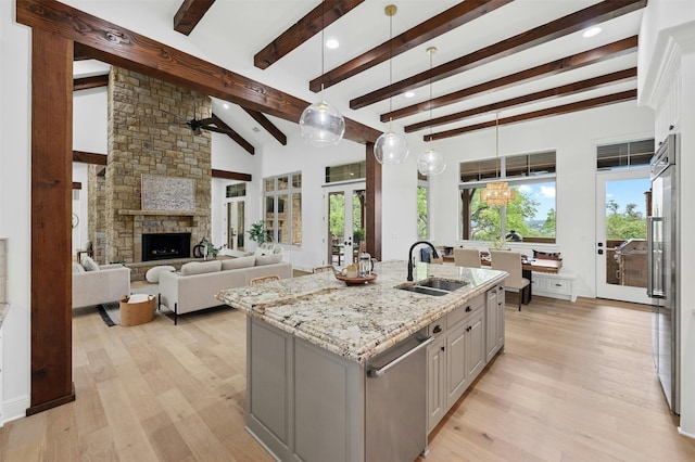 kitchen with sink, hanging light fixtures, an island with sink, and beam ceiling