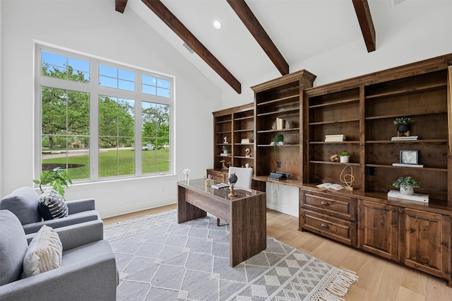 office space with a towering ceiling, light wood-type flooring, and beam ceiling