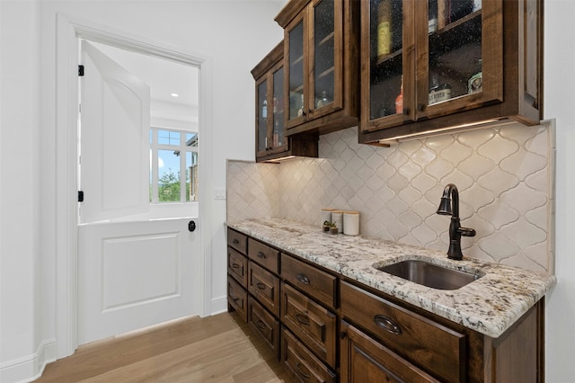 kitchen featuring sink, light hardwood / wood-style flooring, light stone counters, and dark brown cabinets