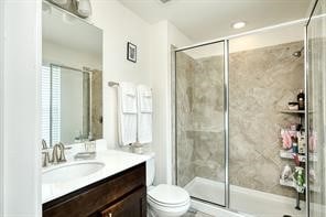 bathroom featuring toilet, an enclosed shower, and vanity