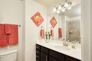 bathroom with a tile shower, vanity, and toilet