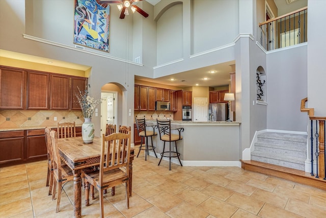 dining space featuring ceiling fan, a high ceiling, and light tile patterned floors