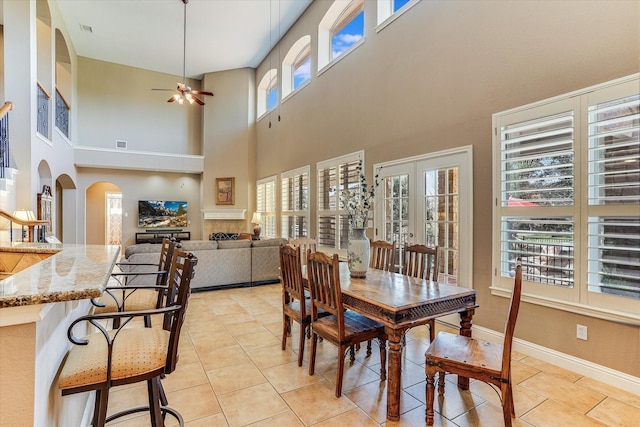 dining room featuring ceiling fan, french doors, light tile patterned floors, and a towering ceiling