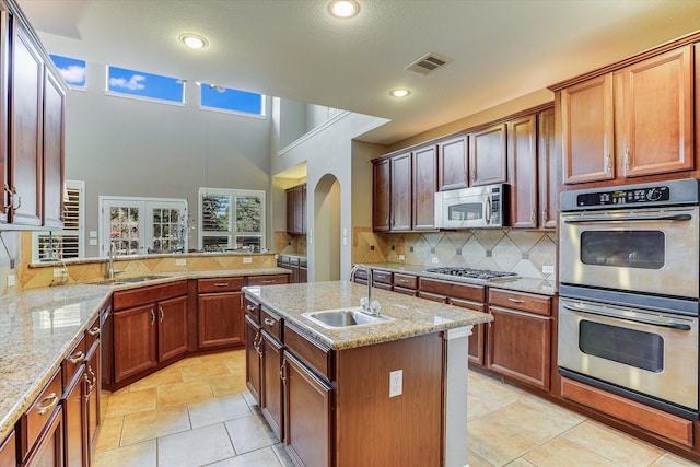 kitchen with sink, an island with sink, light tile patterned floors, and stainless steel appliances