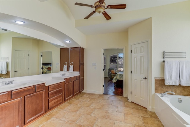 bathroom with tile patterned floors, vanity, a tub to relax in, vaulted ceiling, and ceiling fan