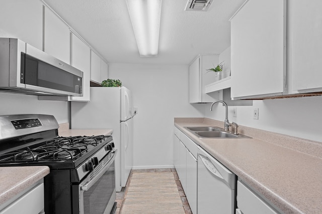 kitchen with stainless steel appliances, white cabinetry, sink, and a textured ceiling