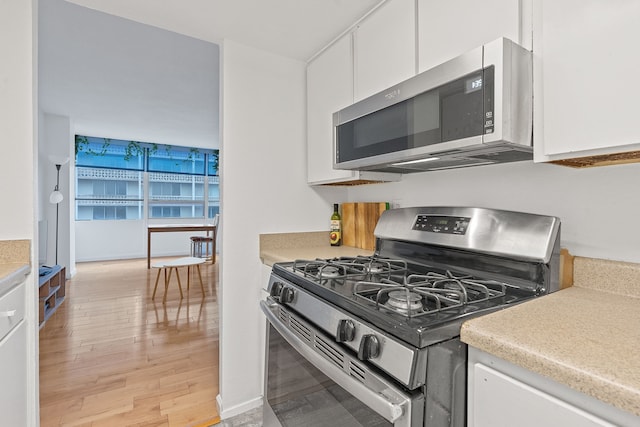 kitchen with stainless steel appliances, light wood-type flooring, and white cabinets