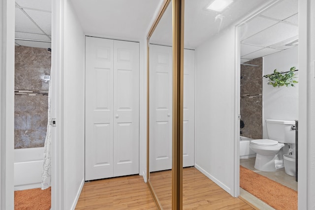 bathroom featuring toilet, shower / bath combo with shower curtain, and wood-type flooring