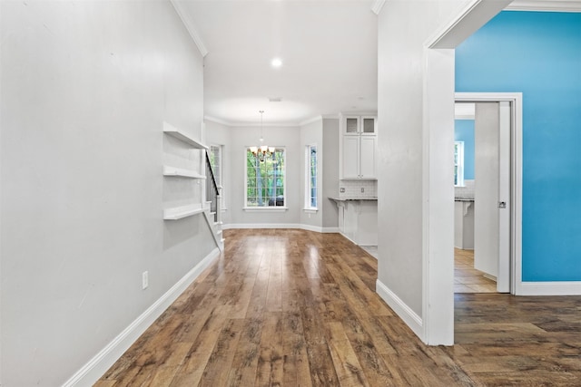 hallway featuring a chandelier, crown molding, and dark hardwood / wood-style floors