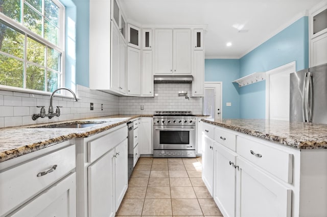 kitchen with sink, white cabinets, light stone counters, light tile patterned floors, and appliances with stainless steel finishes