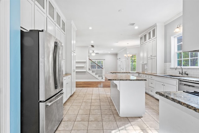 kitchen featuring a kitchen bar, white cabinetry, ceiling fan with notable chandelier, appliances with stainless steel finishes, and sink