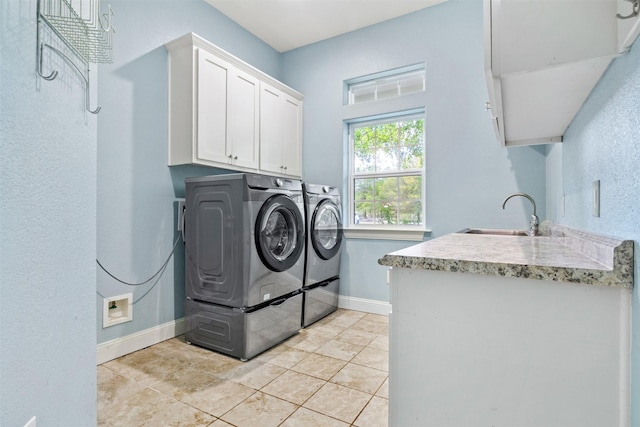 washroom with cabinets, light tile patterned floors, washer and clothes dryer, and sink