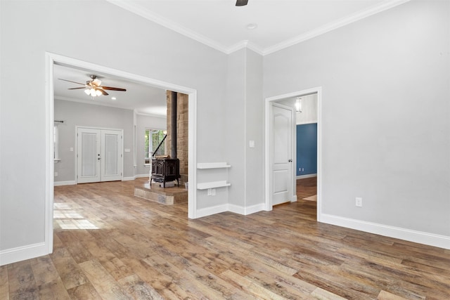 unfurnished room featuring hardwood / wood-style flooring, built in features, crown molding, and a wood stove