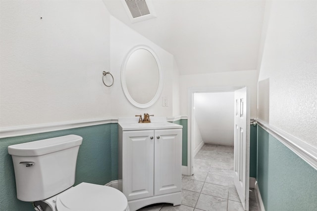 bathroom featuring toilet, tile patterned flooring, vanity, and lofted ceiling