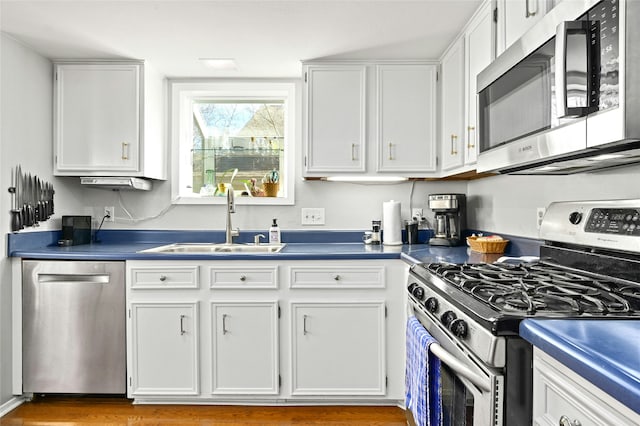 kitchen with stainless steel appliances, wood-type flooring, white cabinets, and sink