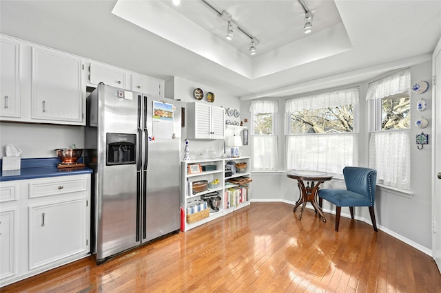 kitchen featuring light hardwood / wood-style flooring, stainless steel fridge with ice dispenser, white cabinetry, and a tray ceiling