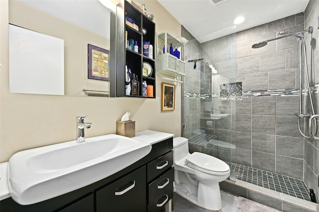 bathroom with toilet, a tile shower, and vanity