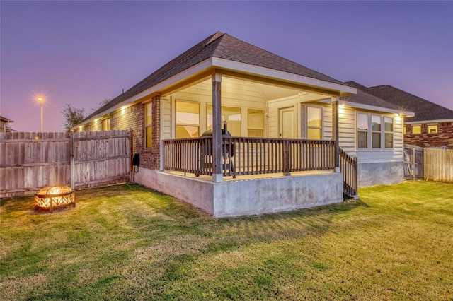 property exterior at dusk with an outdoor fire pit and a yard