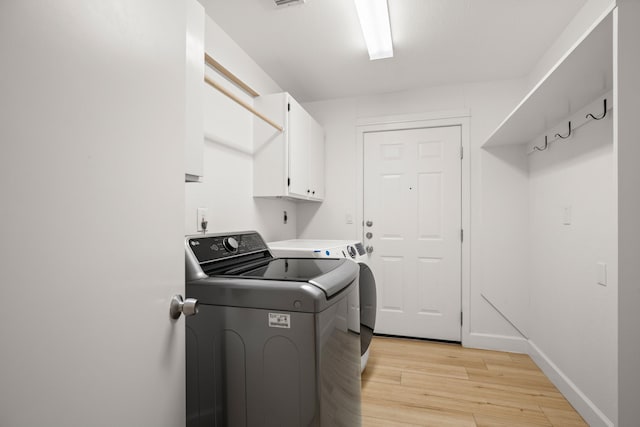 laundry area with washer and dryer, cabinets, and light wood-type flooring