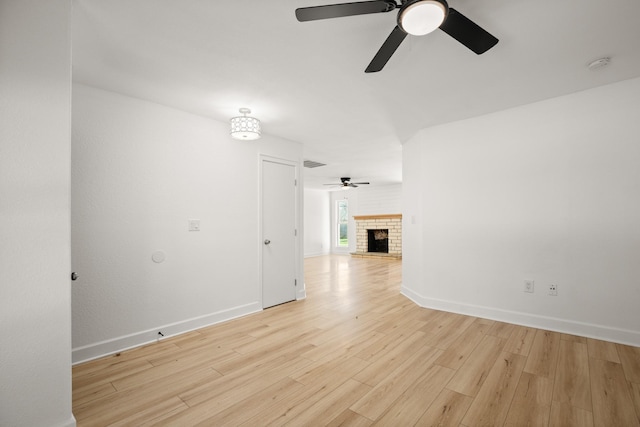 unfurnished living room featuring a brick fireplace, light hardwood / wood-style floors, and ceiling fan