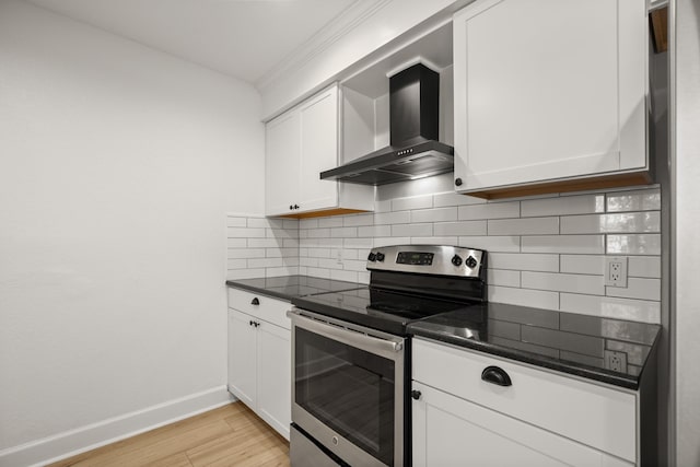 kitchen featuring stainless steel electric range, wall chimney range hood, and white cabinetry