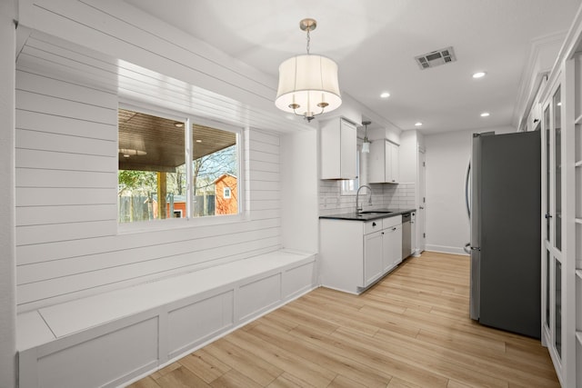 kitchen featuring backsplash, pendant lighting, sink, white cabinetry, and appliances with stainless steel finishes