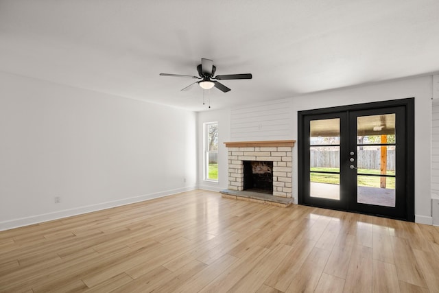 unfurnished living room featuring light wood-type flooring, french doors, a fireplace, and ceiling fan